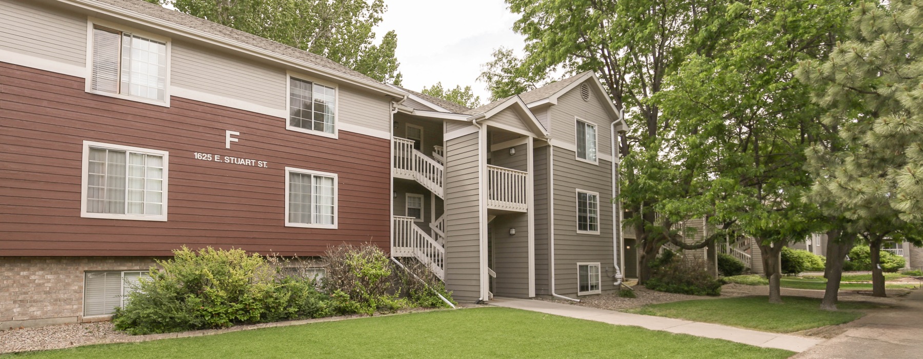 Apartment building with red siding surrounded by trees